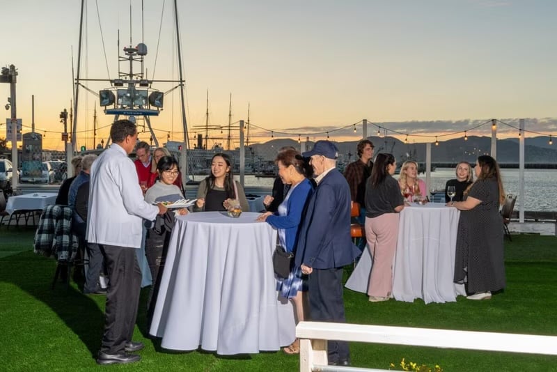 Guests networking at golden hour on the bayside patio at Scoma's